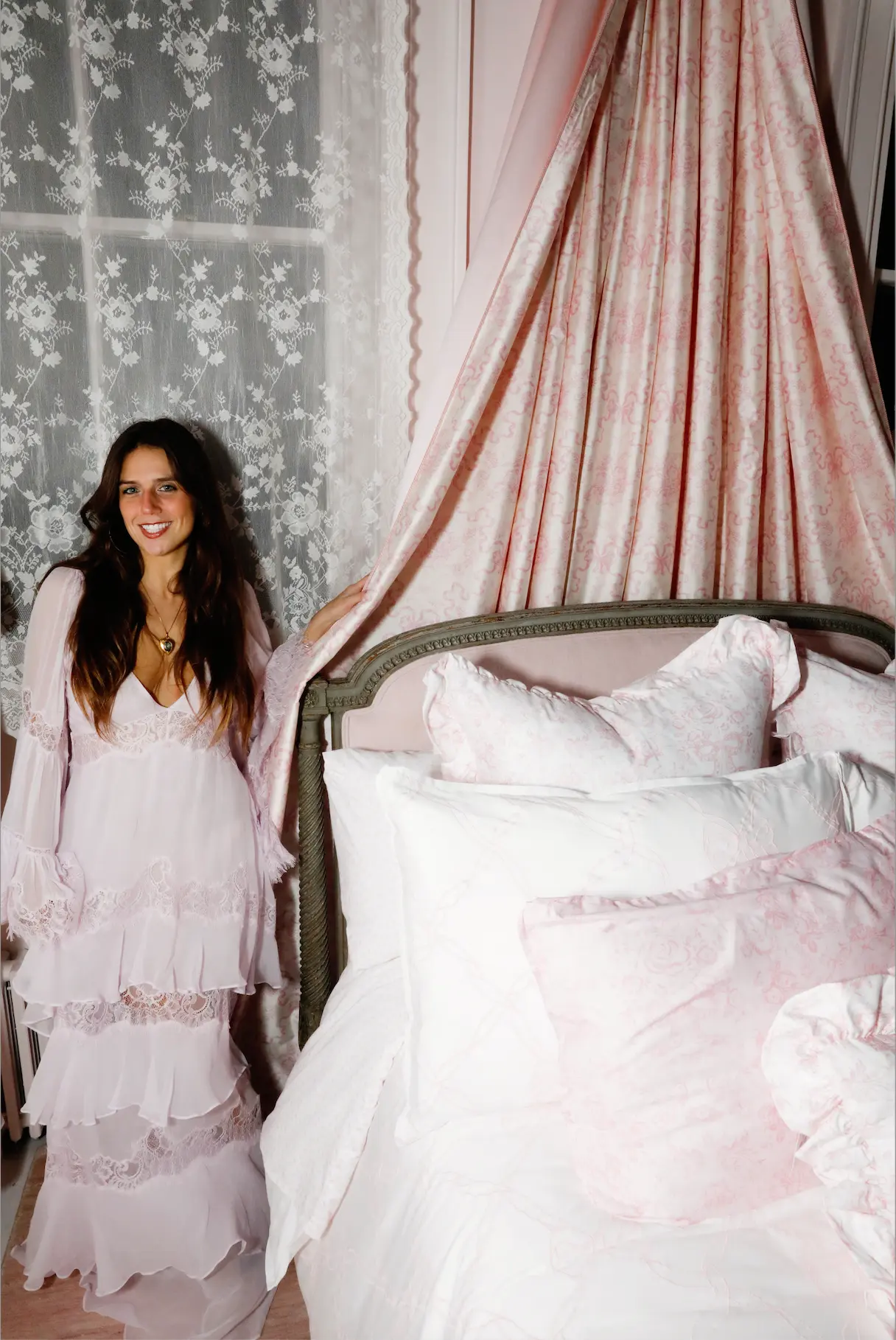 KT Dorfman in a pink ruffled dress in a floral bedroom for a Love Shack Fancy advertisement