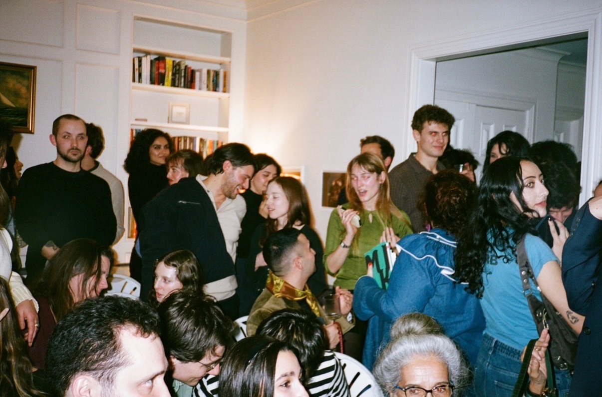 A crowded room of guests at a poetry reading