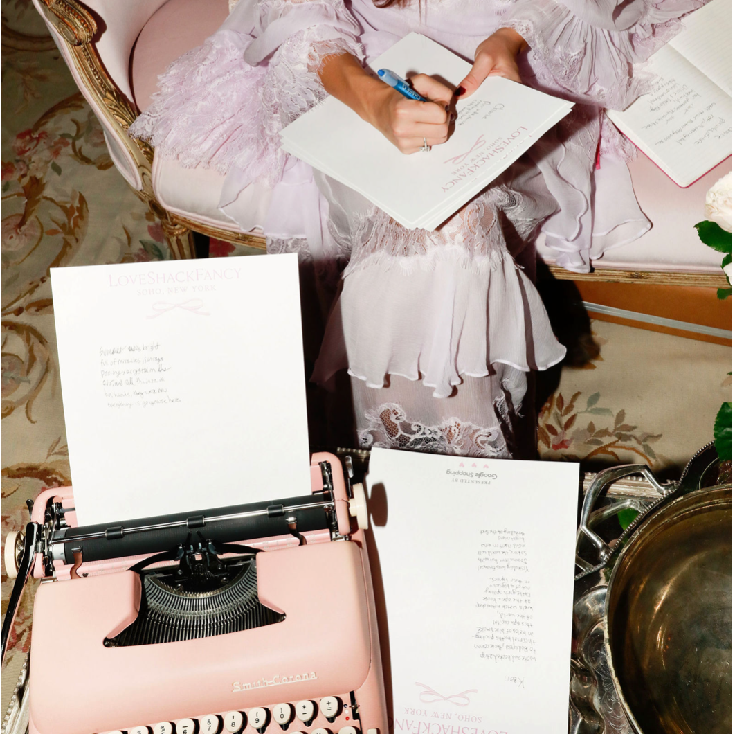 A pink Smith-Corona typewriter with Love Shack Fancy paper and a handwritten poem