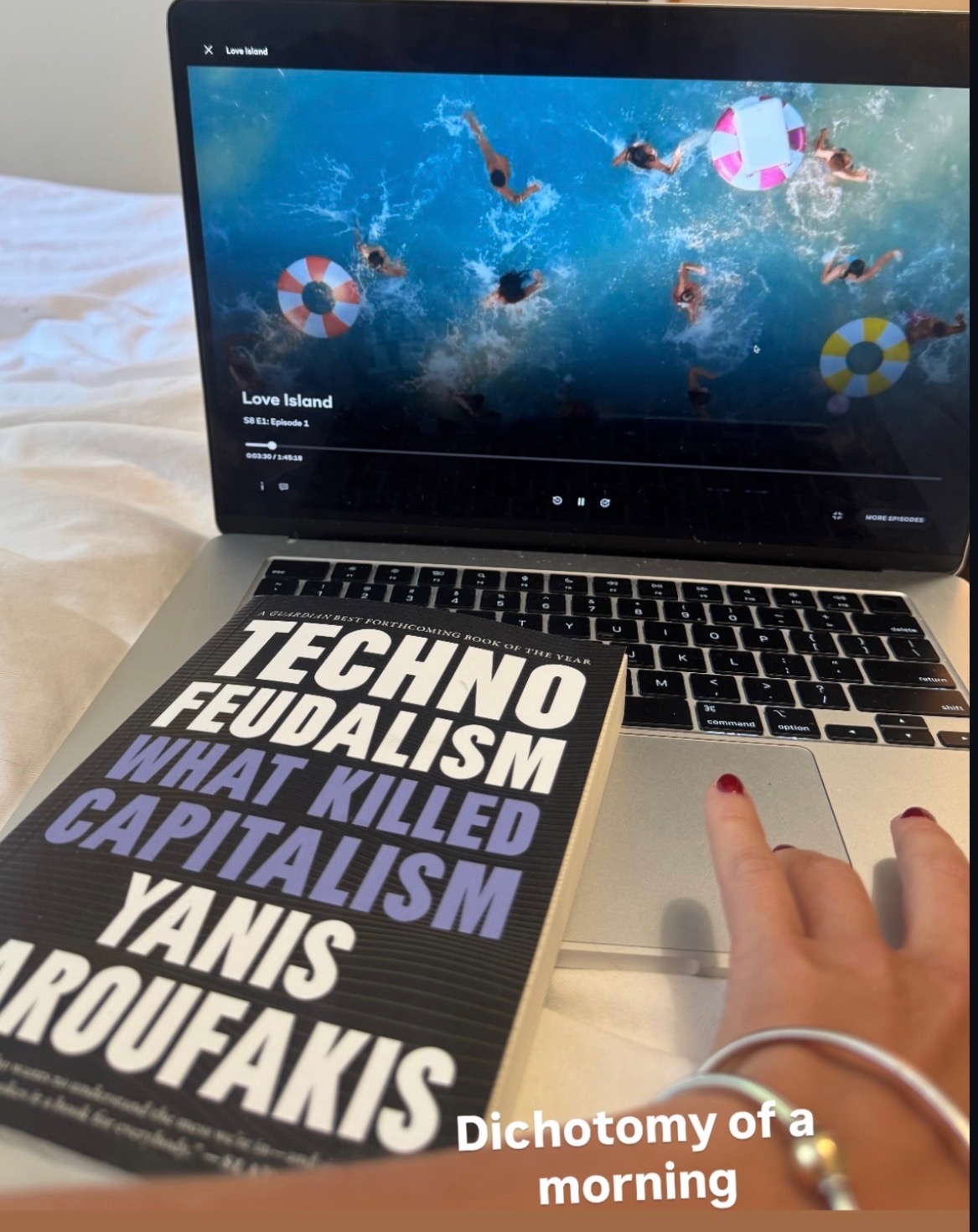 Laptop showing Love Island and the book Techno Feudalism by Yanis Varoufakis