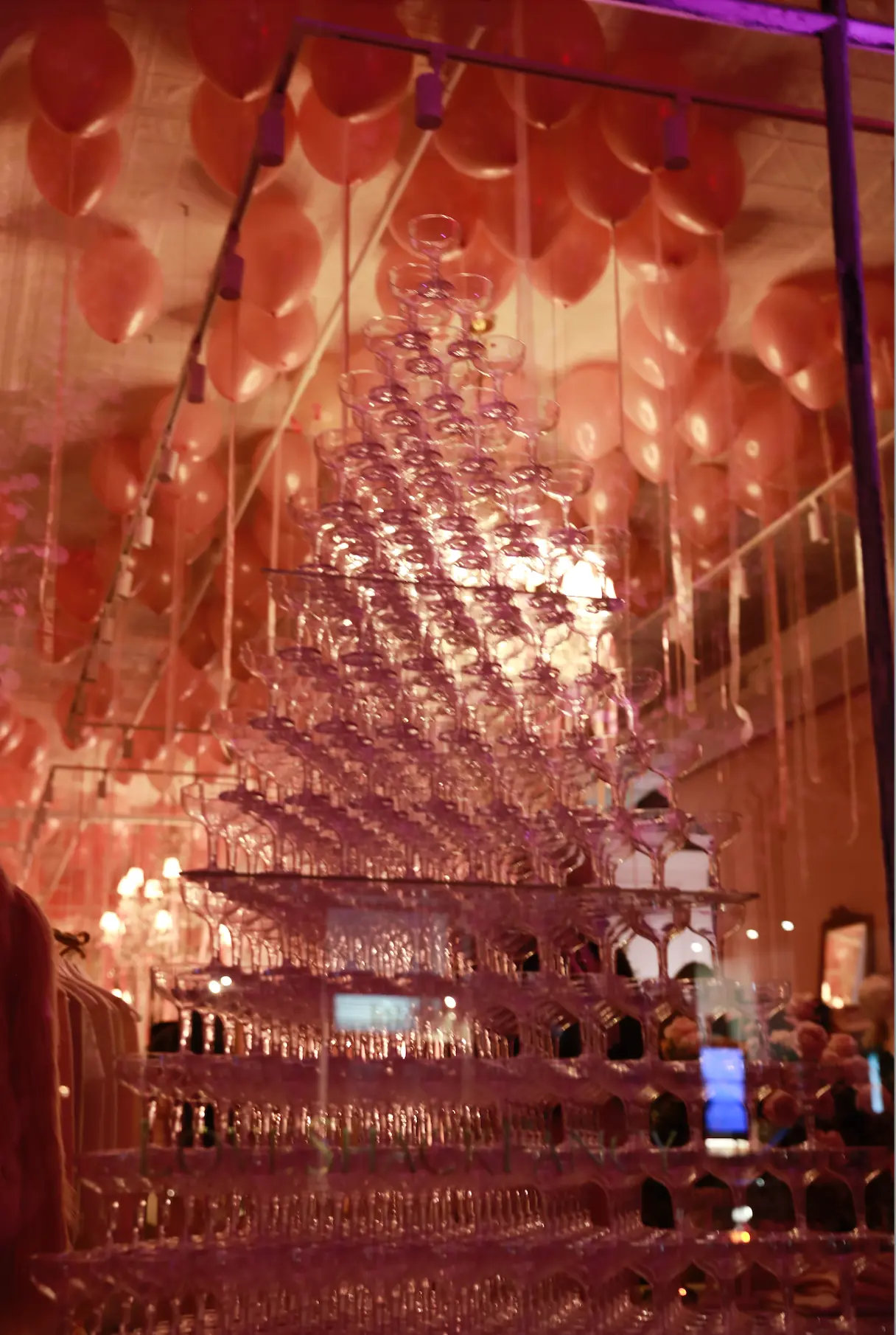 A glowing tower of champagne glasses at a Love Shack Fancy event