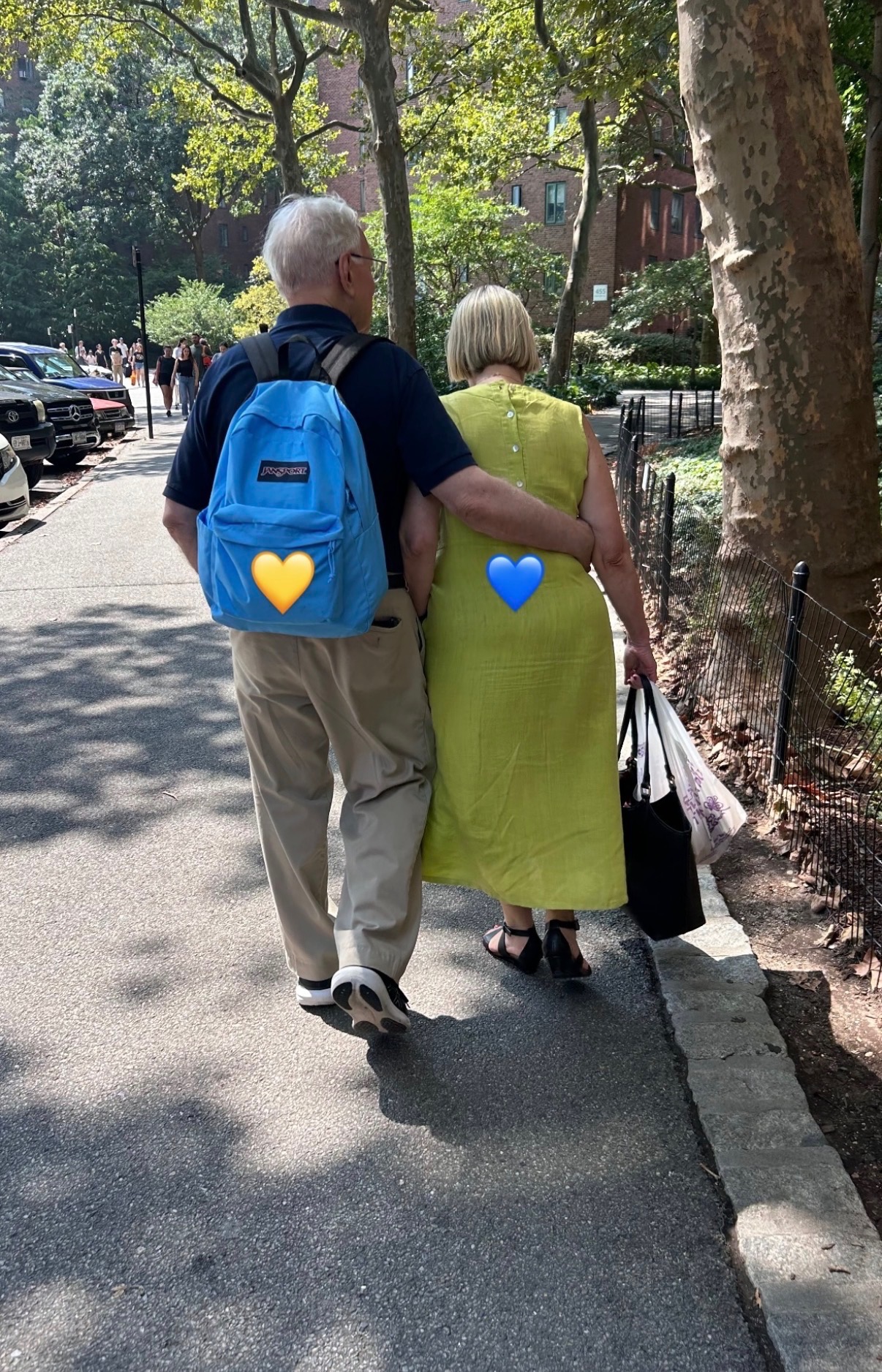 Couple walking in a park with a blue backpack, heart stickers