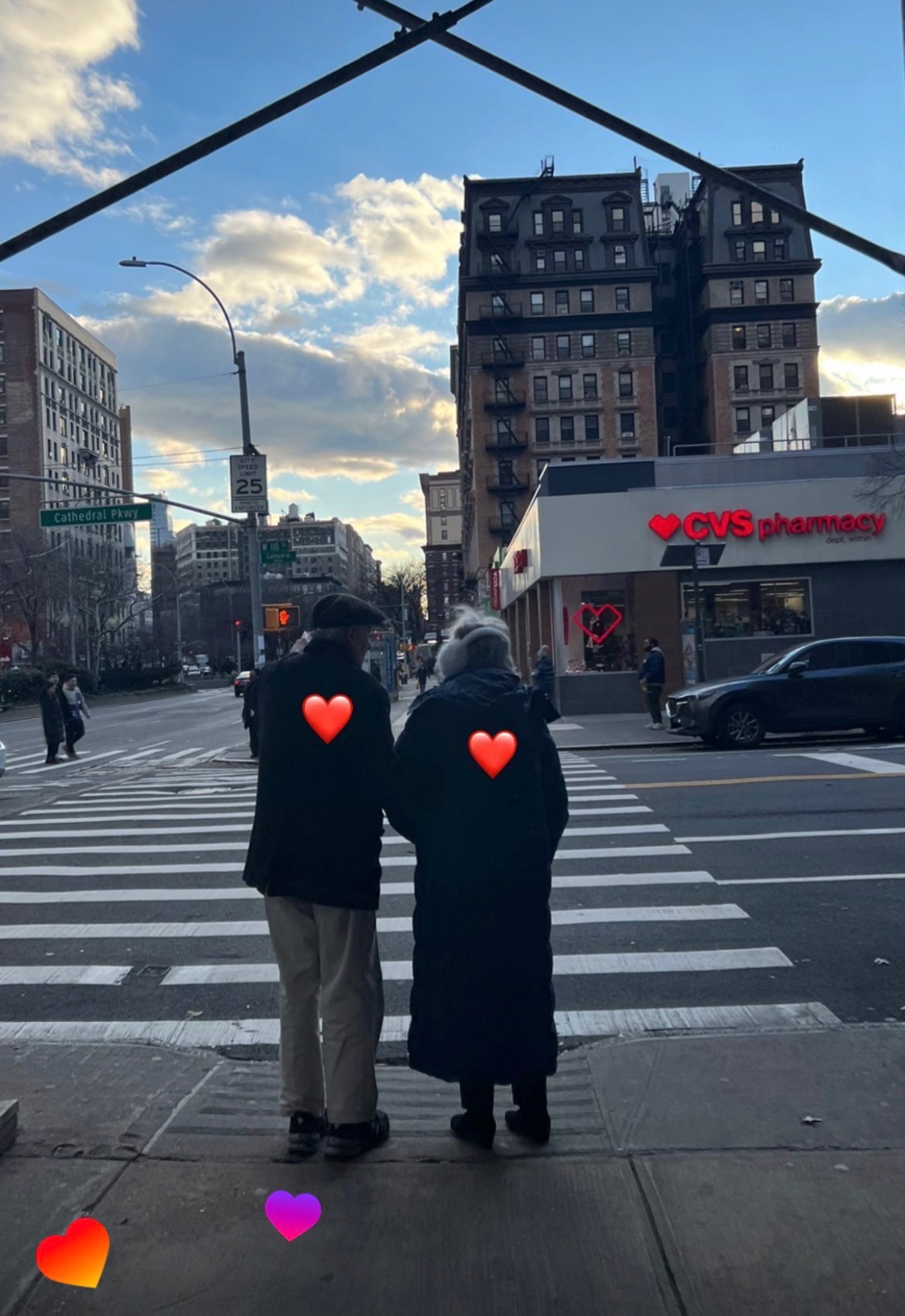 Older couple crossing the street near a CVS, with heart stickers