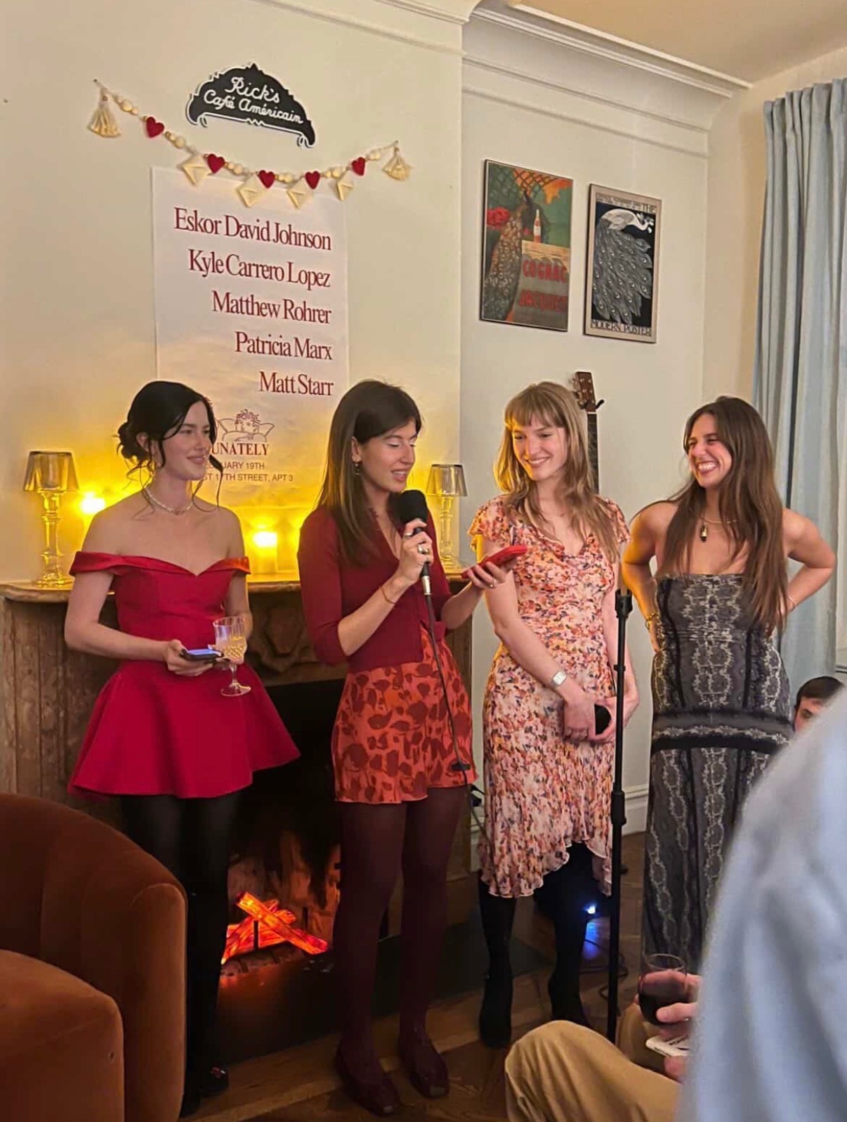 Four women reading at a poetry event by a fireplace