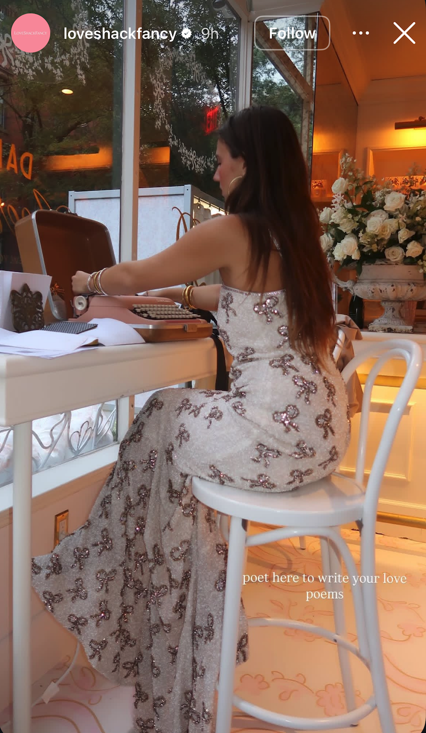 KT Dorfman typing on a pink typewriter at a Love Shack Fancy event